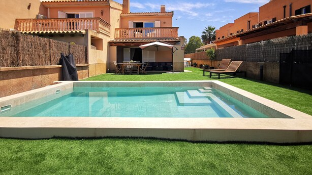 Una piscina con area solarium, una zona relax coperta e vista su un edificio a più piani con balconi.