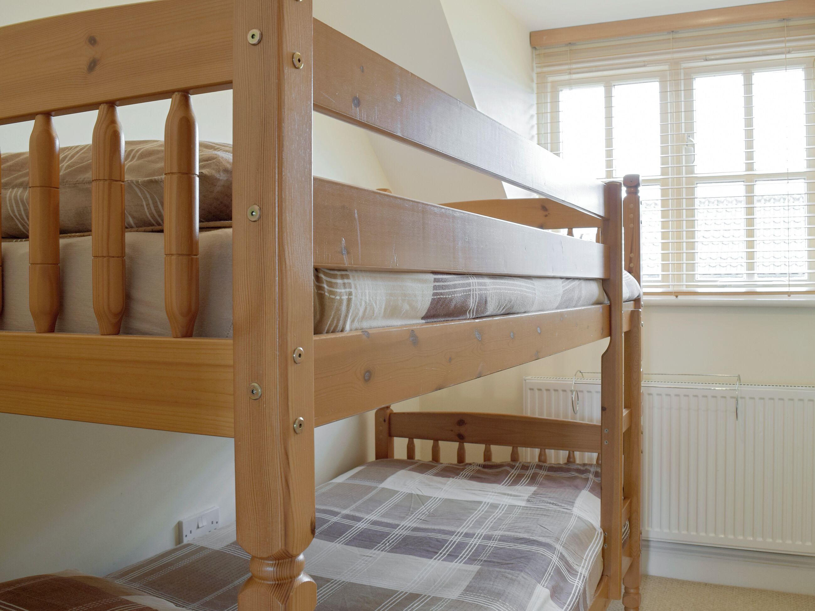 Ein Stockbett mit Holzbettgestell und einem Karomuster-Matratze.