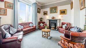 A traditional living room with leather sofas, a fireplace, and framed artwork on the walls. - 7 bedroom accommodation in Portpatrick (Portpatrick)
