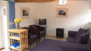 A cozy living room with a wooden ceiling, a television, a small cabinet, and a sofa. - A delightful little barn conversion situated in a tranquil area of Cumbria. (Ellonby)