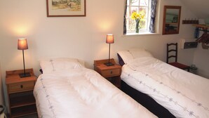 A room with two single beds, a nightstand with lamps, a window with curtains, a mirror, and a framed painting on the wall. - A delightful little barn conversion situated in a tranquil area of Cumbria. (Ellonby)