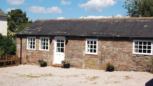 A stone cottage with a tiled roof, a wooden door, and three windows. There are flower pots in front of the cottage. - A delightful little barn conversion situated in a tranquil area of Cumbria. (Ellonby)