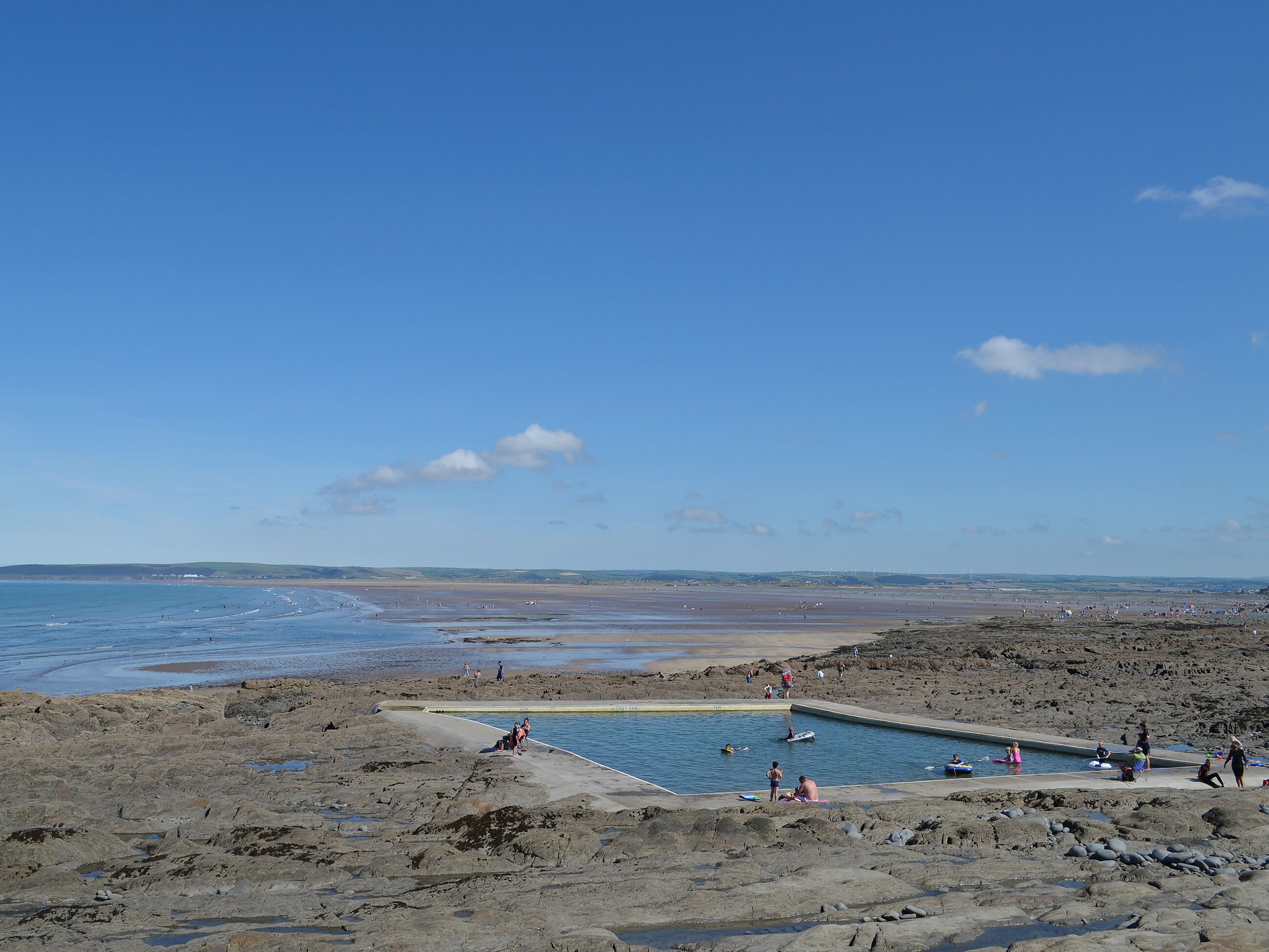 Una playa con piscina rodeada de terreno rocoso.