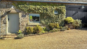 A stone cottage with a sloped roof, two skylights, a small window with a view, and a gravel driveway. - 2 bedroom accommodation in Almondbury (Almondbury)