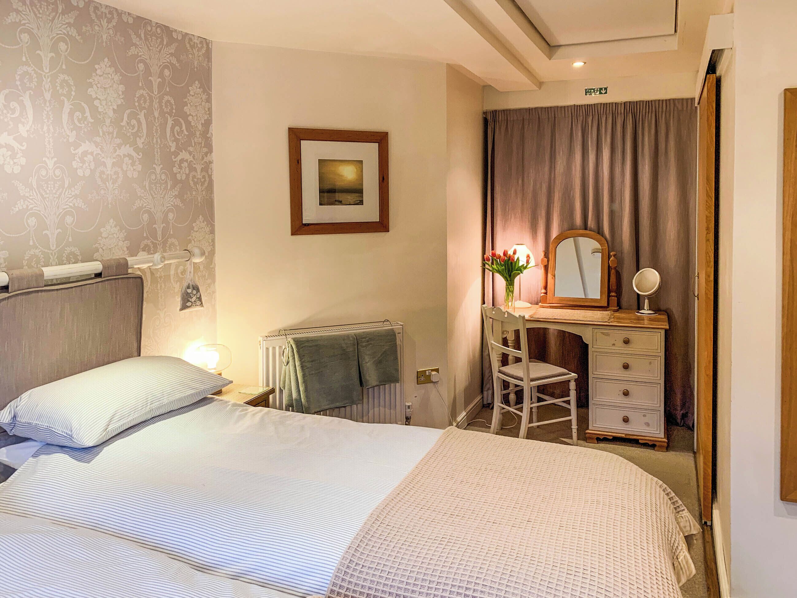 Una habitación de hotel con una cama, un escritorio con espejo y un radiador.
