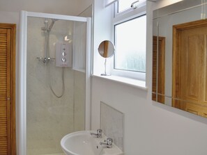 Une salle de bain avec une douche, un lavabo, un miroir et des portes en bois.
