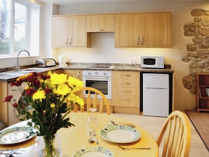 A kitchen with wooden cabinets, a microwave, a dishwasher, and a dining table set with plates and cutlery.