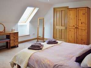 Une chambre à coucher avec un lit, une commode, un miroir et une armoire.