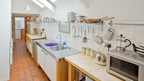 A modern kitchen with a skylight, stainless steel appliances, and hanging utensils. - 4 bedroom accommodation in Dulverton (Dulverton)
