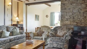 Ein gemütliches Wohnzimmer mit gemusterten Sofas, einem Holztisch, einem Kamin aus Stein und einem Fernseher.