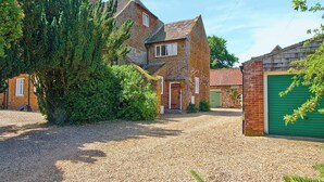A stone house with a gravel driveway and a green garage door. - 2 bedroom accommodation in Old Hunstanton (Old Hunstanton)