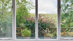 A room with large windows offering a view of a garden with various plants and a wooden fence. - 3 bedroom accommodation in Oughtershaw, near Hawes (Oughtershaw, near Hawes)