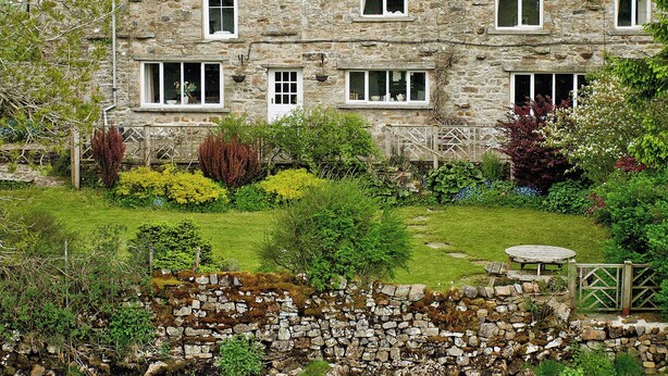 A stone house with multiple windows and a garden with various plants and a stone wall. - 3 bedroom accommodation in Oughtershaw, near Hawes (Oughtershaw, near Hawes)