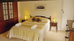 A neatly made bed with pillows and a blanket, a bedside table with a lamp, a wooden chair, and a door with glass panels. - 3 bedroom accommodation in Oughtershaw, near Hawes (Oughtershaw, near Hawes)