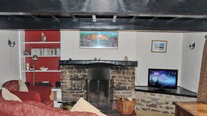 A living room with a fireplace, red sofas, a bookshelf, and a television. - 3 bedroom accommodation in Oughtershaw, near Hawes (Oughtershaw, near Hawes)