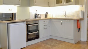 A compact kitchen with a microwave, toaster, kettle, sink, and oven. - The Wood Shed - E1919 (Hinton, near Dunwich)