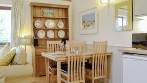 A cozy dining area with wooden furniture, a shelf with decorative plates, and a framed landscape painting. - The Wood Shed - E1919 (Hinton, near Dunwich)