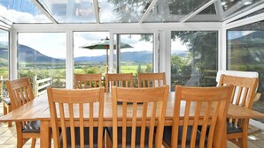 A conservatory with a wooden table and chairs, large windows, and a view of the countryside. - 4 bedroom accommodation in Bassenthwaite, near Keswick (Bassenthwaite, near Keswick)