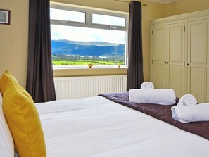Una habitación de hotel con una cama, un ventanal con vistas a montañas y un radiador.