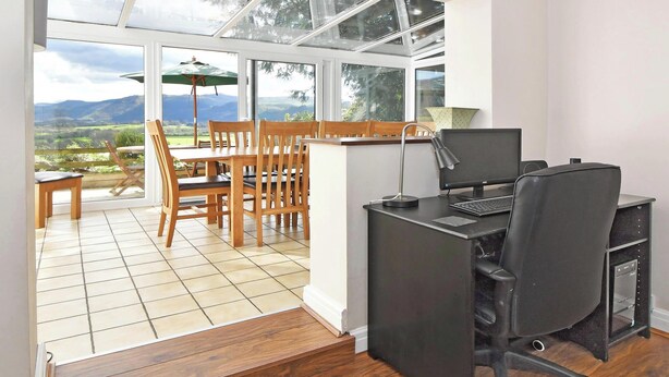 A conservatory with a dining area, a desk with a computer, and a view of the outdoors. - 4 bedroom accommodation in Bassenthwaite, near Keswick (Bassenthwaite, near Keswick)