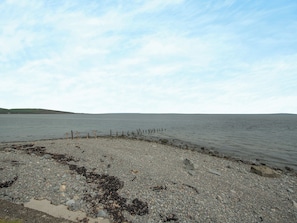 A rocky shoreline with a calm sea and a clear sky.