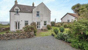 Une maison à deux étages avec un mur en pierre et une allée gravillonnée.