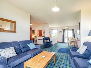 A modern living room with sofas, a coffee table, and a dining area with chairs and a table.