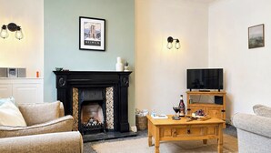A living room with a fireplace, a television, and a coffee table. - 2 bedroom accommodation in Keswick (Keswick)
