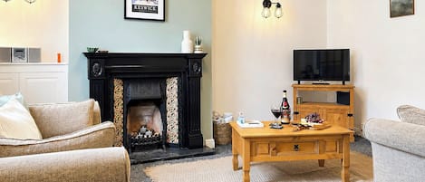 Ein Wohnzimmer mit Kamin, Fernseher und Couchtisch.