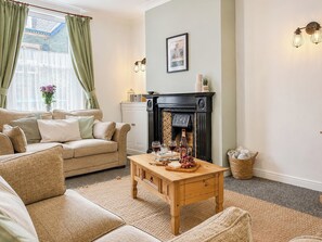 A cozy living room with a sofa, a wooden coffee table, and a fireplace.