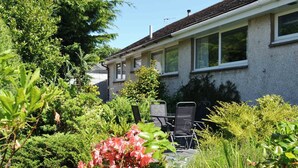 Ein Wohnhaus mit Garten, Sitzgelegenheiten im Freien und blauem Himmel.