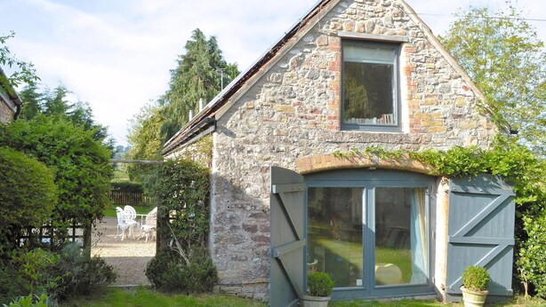 A stone house with a large window and a sliding door.
