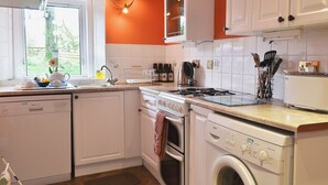 Una cocina con armarios blancos, un lavavajillas Bosch, una estufa y una lavadora.