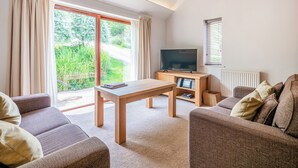 Ein modernes Wohnzimmer mit großem Fenster, Flachbildfernseher und Couchtisch aus Holz.