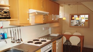Une cuisine compacte dotée de meubles en bois, d’une cuisinière, d’un lave-vaisselle et d’un coin repas avec une table et des chaises.