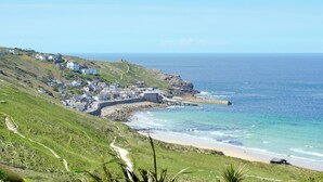 Un pueblo costero con un litoral rocoso, una playa y un sendero que baja al mar.