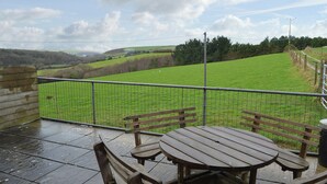 A patio with a table and benches overlooking a green field with sheep. - 3 bedroom accommodation in St Mawgan, near Newquay (St Mawgan, near Newquay)