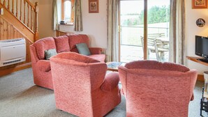 A living room with a wooden staircase, a fireplace, and a large sliding glass door to the outside. - 3 bedroom accommodation in St Mawgan, near Newquay (St Mawgan, near Newquay)