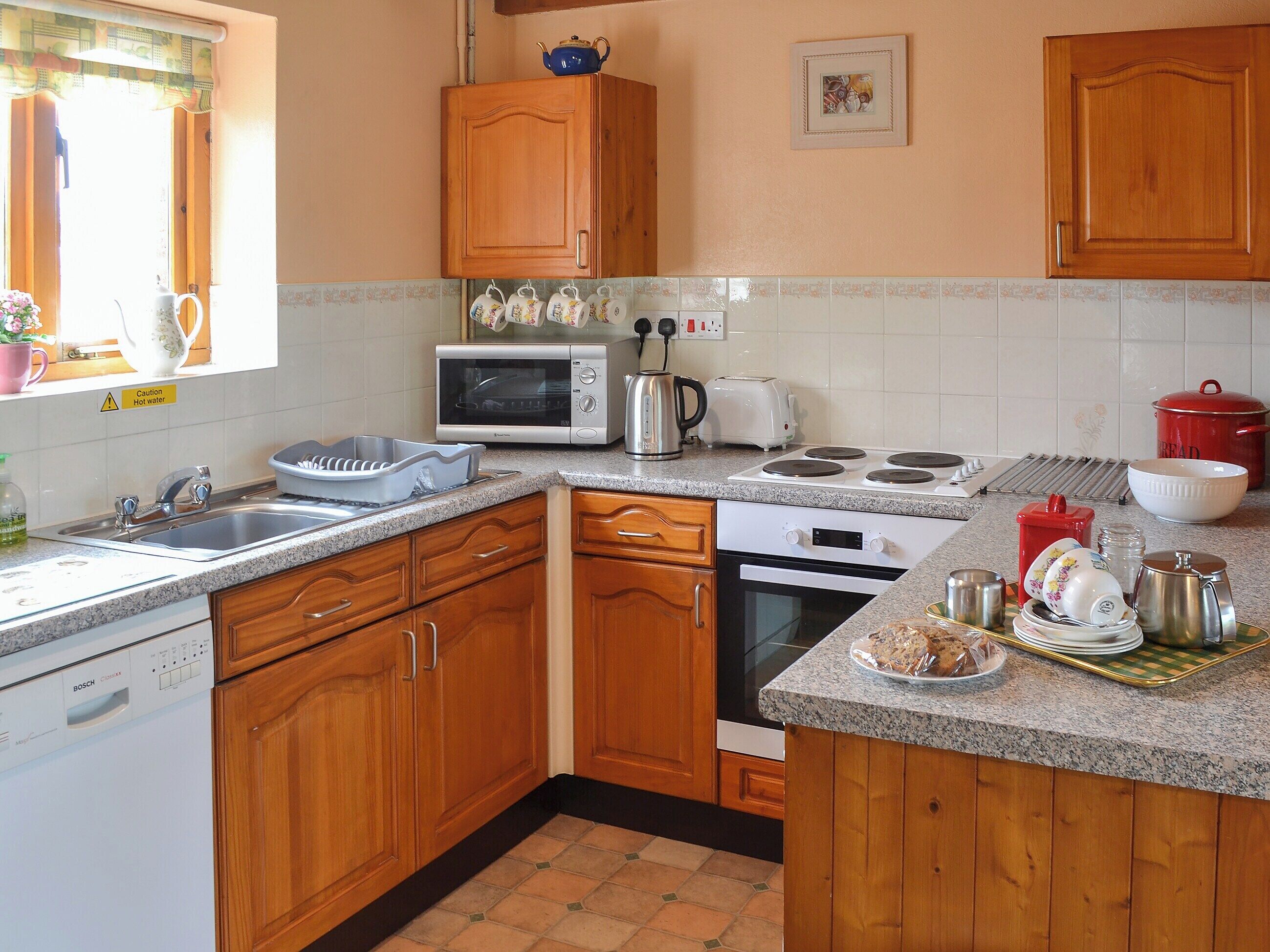 A kitchen with wooden cabinets, a microwave, a toaster, and a sink.