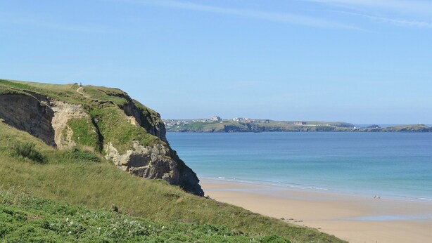 A coastal landscape with a sandy beach, grassy cliffs, and a clear blue sky. - 3 bedroom accommodation in St Mawgan, near Newquay (St Mawgan, near Newquay)