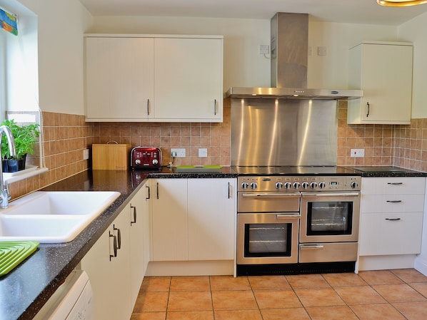 A kitchen with white cabinets, a stainless steel range hood, and a double oven.