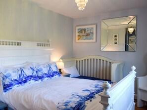 A bedroom with a bed, a nightstand, a lamp, a painting, and a mirror.