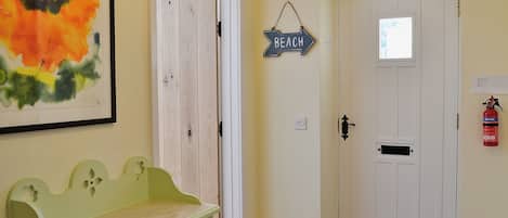 Un pasillo con un banco, una puerta con la etiqueta 'BEACH' y un extintor.