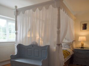 A four-poster canopy bed with a white bedspread and a blue headboard. - 4 bedroom accommodation in Bothenhampton, near Bridport (Bothenhampton, near Bridport)