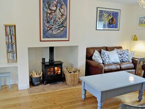 A living room with a fireplace, a leather sofa, a table, and a bookshelf.