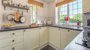 A modern kitchen with white cabinets, a black countertop, and a window with a view of greenery. - 2 bedroom accommodation in Haytongate, near Brampton (Haytongate, near Brampton)