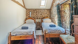 A bedroom with two wooden beds, a stone wall, a skylight, and a wooden dresser. - 2 bedroom accommodation in Haytongate, near Brampton (Haytongate, near Brampton)