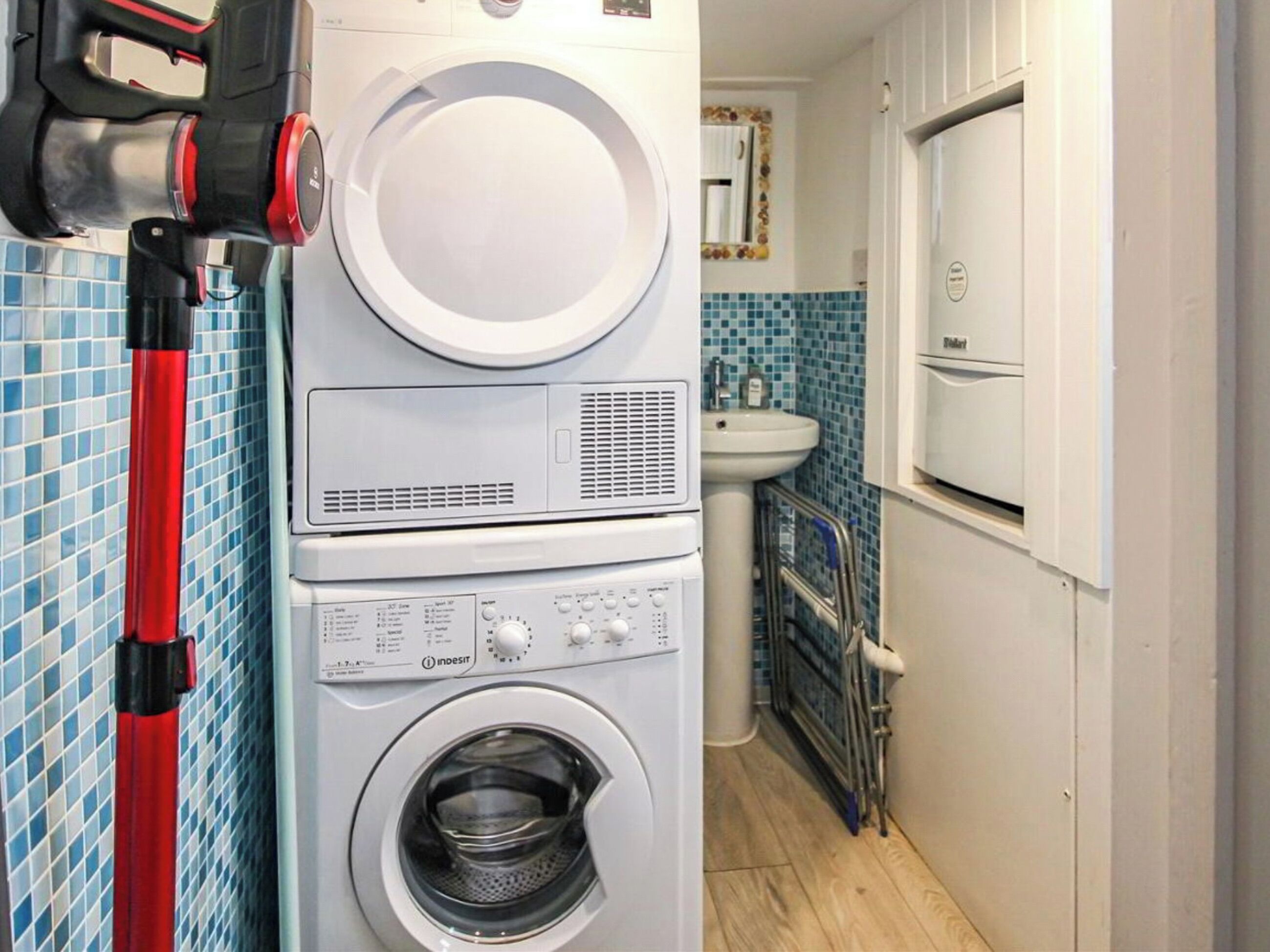 Een wasserette met gestapelde wasmachines, een wasbak en een raam met decoratief kader.