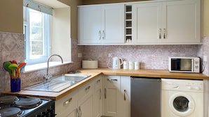 Een moderne keuken met een fornuis, spoelbak, magnetron en vaatwasser.