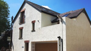 A two-story building with a garage, a balcony, and a small window. - 2 bedroom accommodation in Keswick (Keswick)